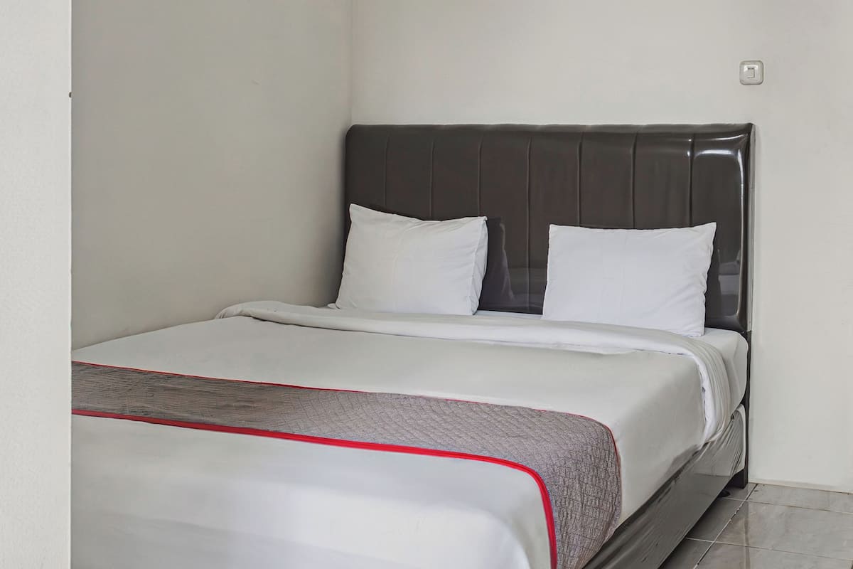 A neatly made bed with white bedding and a grey headboard.