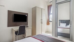 A hotel room with a bed, a desk with a chair, a wardrobe, a television mounted on the wall, and a sliding glass door leading to a balcony. - Collection O Bogor Near Ipb University Formerly Yasmin (Dramaga)