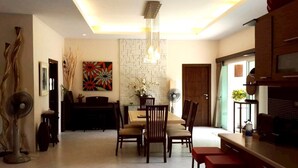 A modern dining area with a wooden table and chairs, a decorative wall, and a ceiling light fixture.
