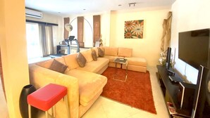 A living room with a sofa, a coffee table, a TV, and a workout area with a treadmill.
