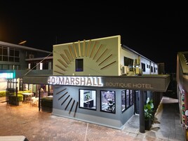 A boutique hotel with a modern design, featuring a prominent sign and a balcony.