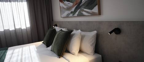 Una habitación de hotel con una cama, un cuadro, un cabecero y una lámpara de pared.