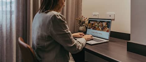 A person using a laptop at a desk with a laptop screen displaying a hotel website.