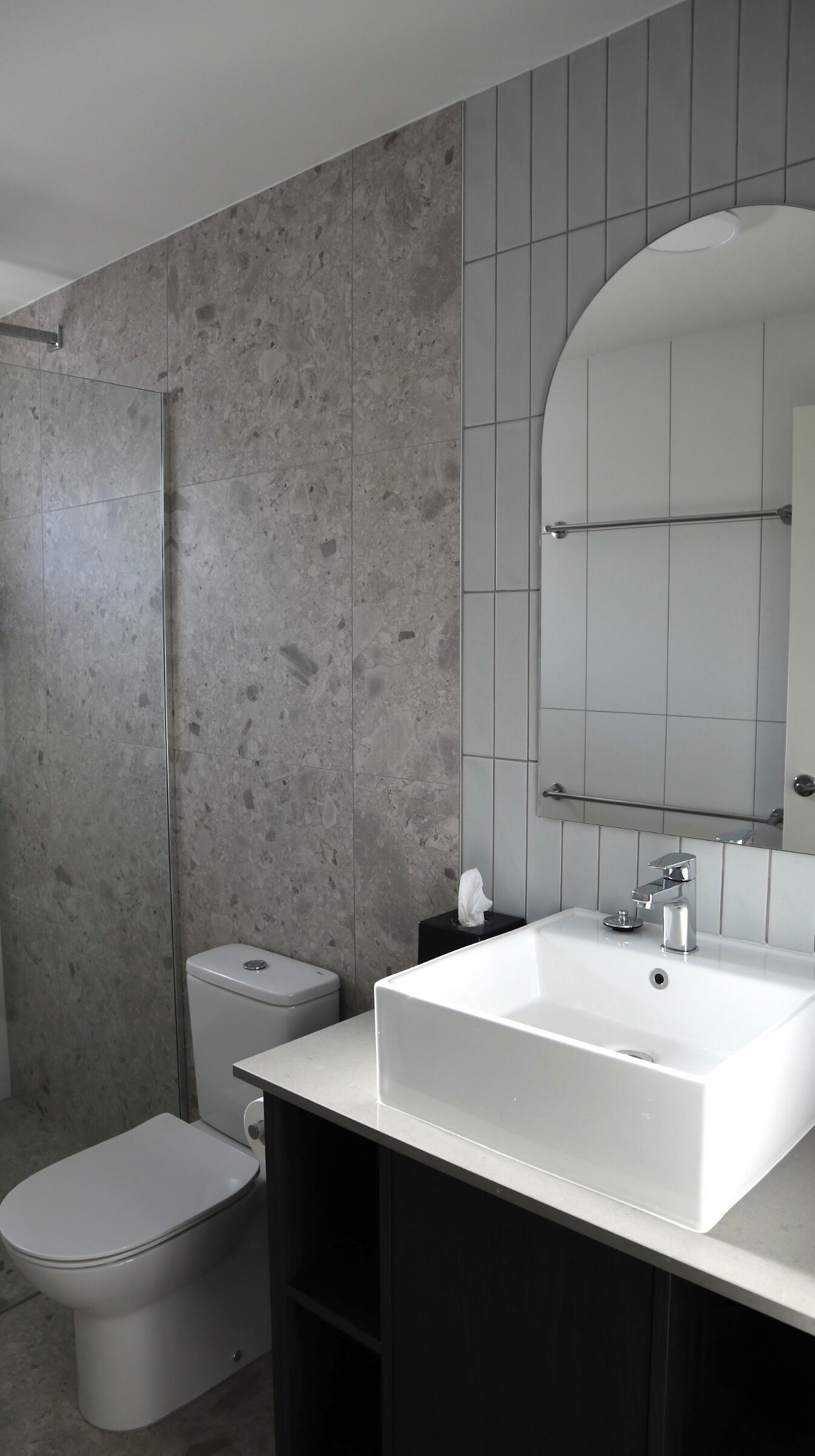 Un baño moderno con un lavamanos blanco, un inodoro y una ducha.