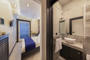 Een moderne hotelkamer met een bed, een badkamer met een grote spiegel en een wastafel.