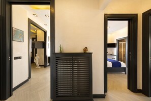 A hallway with a black console table, a white statue, and a bed in the background.