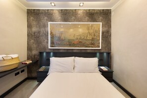 Ein modernes Schlafzimmer mit einem großen Bett, einem an der Wand montierten Kopfteil mit integrierter Beleuchtung, einem Nachttisch mit Lampe und einem Wandbild.