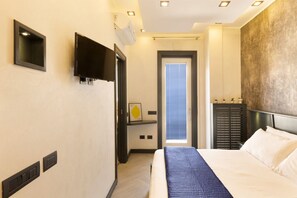 A hotel room with a bed, a TV mounted on the wall, a door leading to a balcony, and a wall-mounted heater. - 3BR Sorrento Apt with SeaView Terrace (Sorrento)
