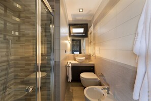 A modern bathroom with a glass-enclosed shower, a toilet, a sink, and a mirror.