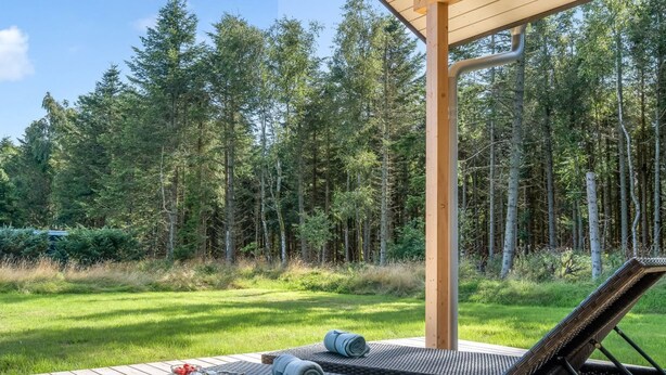 A deck with a wicker sofa and a grill, surrounded by a forest. - "Gedda" -  from the sea by Interhome (Hals)