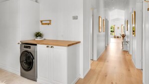 A hallway with a washing machine, wooden counter, and white walls. - "Gedda" -  from the sea by Interhome (Hals)