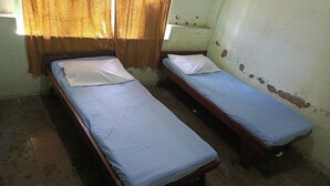 Two single beds with wooden frames and blue bedding in a room with peeling paint on the walls. - Hotel O Agung Banjarnegara (Banjarnegara)