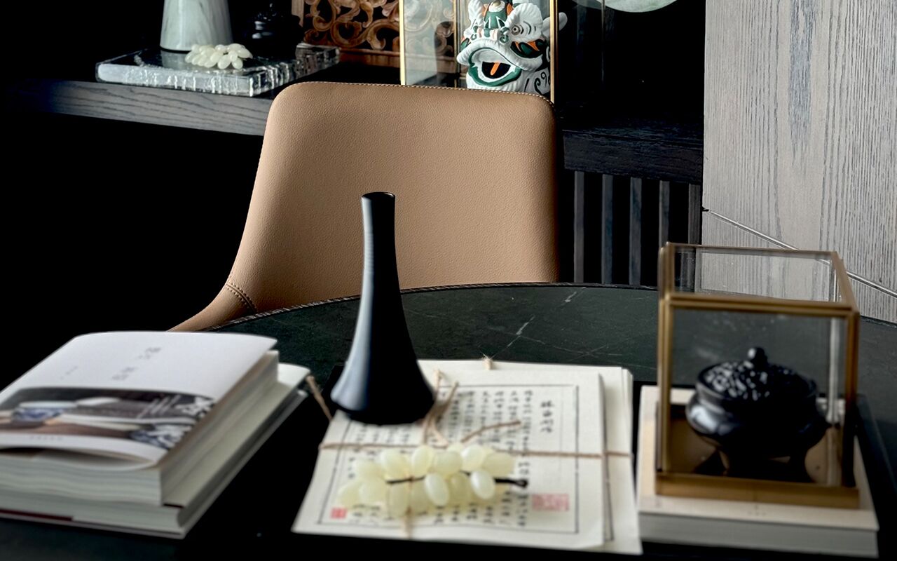 A table with a book, a black vase, a framed picture, and a small decorative item.