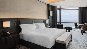 A hotel room with a large bed, bedside tables, a desk, and a view of the sea. - WHITE SWAN HOTEL SHANTOU (Shantou)