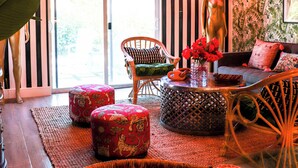 Una habitación con papel tapiz a rayas, una planta grande, muebles de mimbre y una estatua.