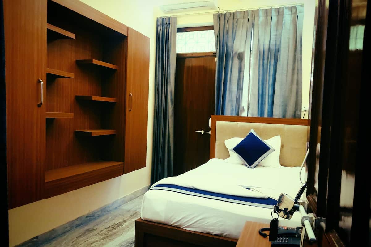 Habitació d'hotel amb llit, escriptori amb telèfon i armari.