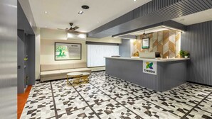 Een receptiegedeelte met een modern design, bestaande uit een receptiebalie, een zithoek en vloertegels met een patroon.