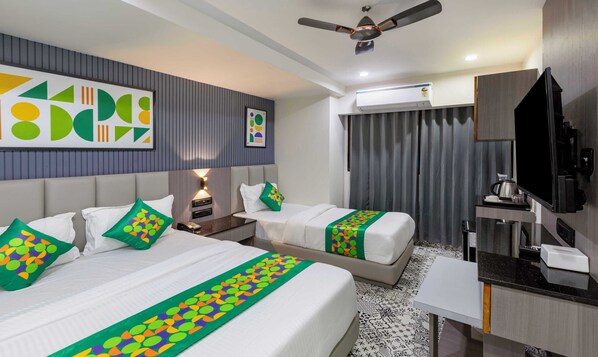A hotel room with two beds, a desk, a TV, and a ceiling fan.