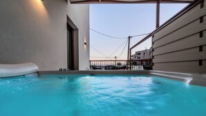 Una piscina interior con agua azul cristalina, vista al cielo y un edificio con balcón al fondo.