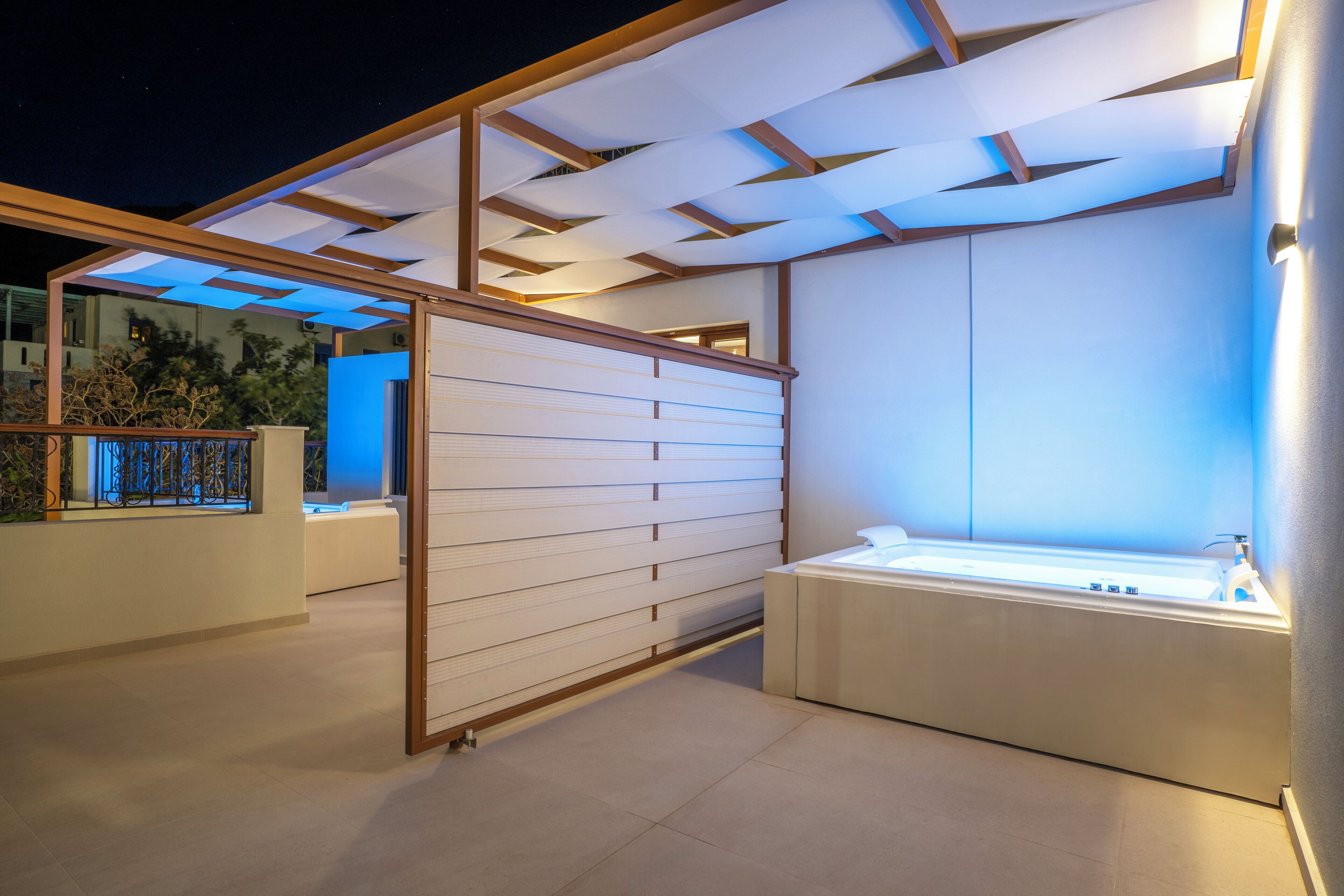 A modern outdoor spa area with a glass enclosure, a white reception desk, and a seating area with a bench.