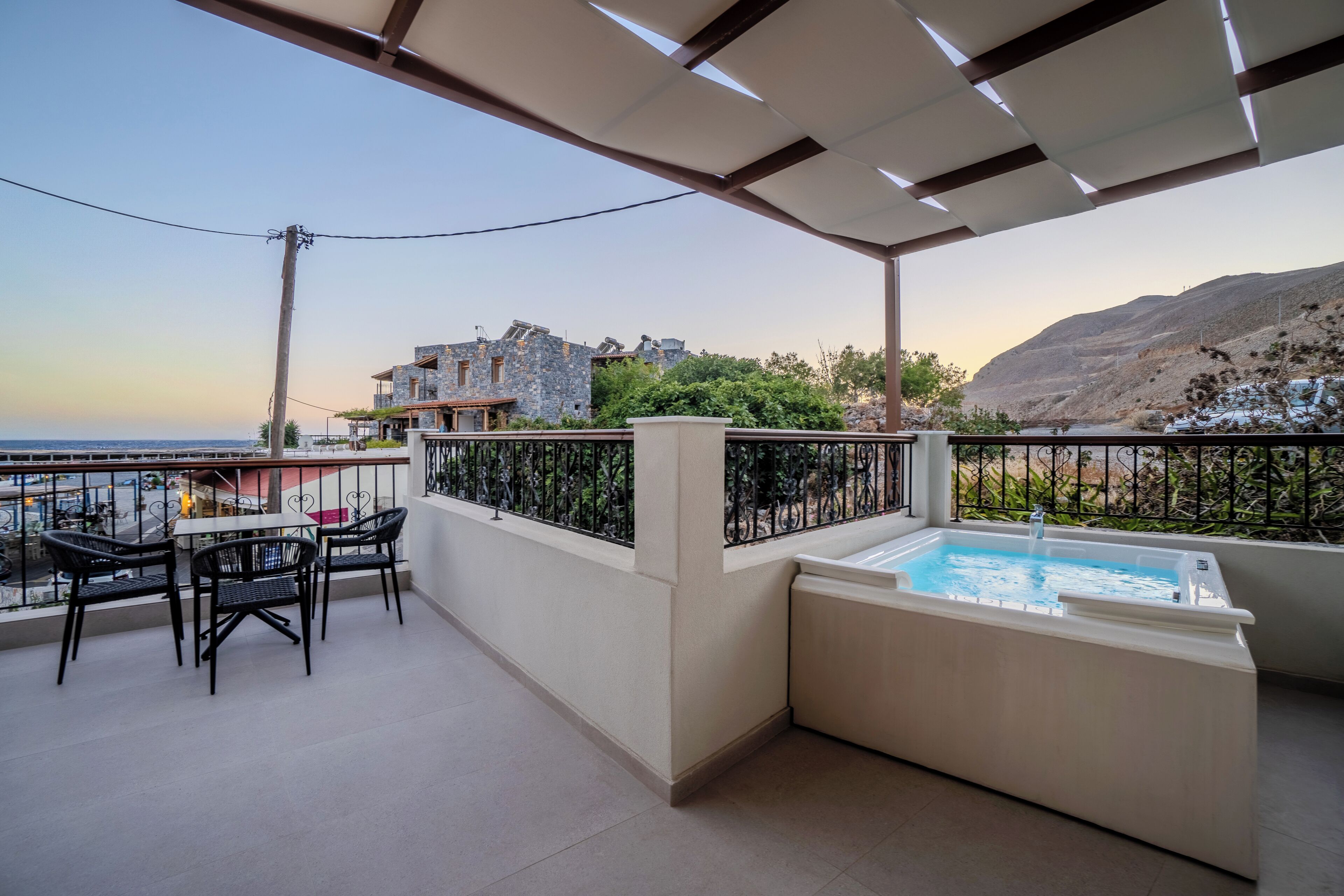 Uma varanda com piscina, mobiliário de exterior e vista para o mar e montanhas.