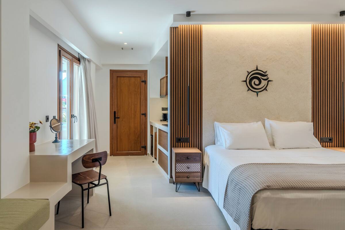 A modern bedroom with a bed, bedside table, and a desk with a chair. There is a wooden panel wall and a wall-mounted artwork.