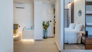 Una habitación de hotel moderna con una cama, mesita de noche y una pequeña zona de estar con sofá y mesa de centro.