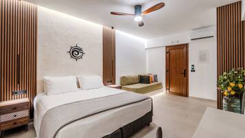 A modern bedroom with a large bed, a ceiling fan, a wooden wall panel, a bedside table, and a nightstand.