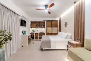 A modern hotel room with a large bed, a desk, and a kitchenette. - VENTUS Luxury Suites (Sfakia)