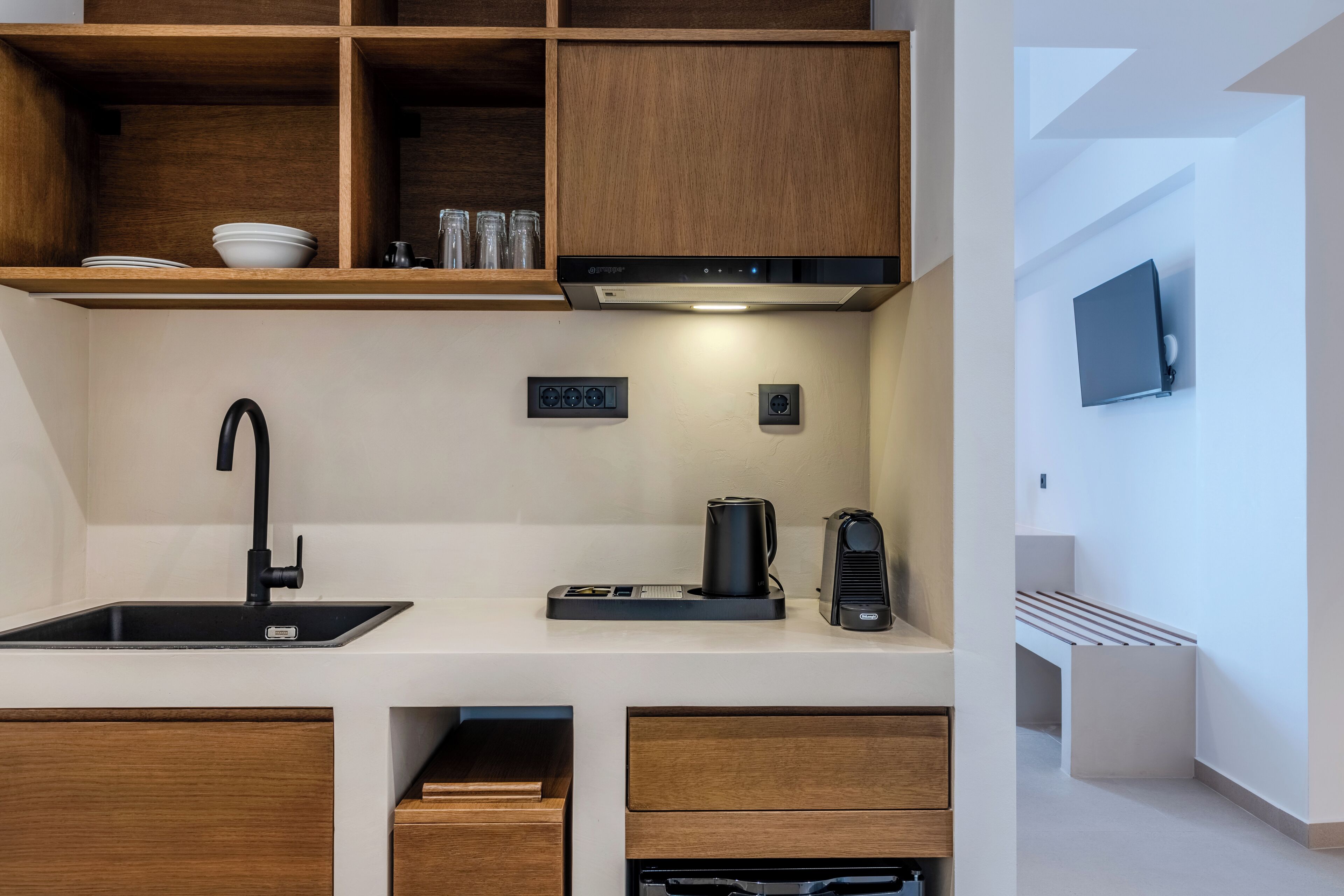 Een moderne keuken met een zwarte kraan, een koffieapparaat en houten kastjes.