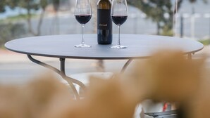 A table with a bottle and two glasses of red wine, set against a cityscape view. - Seaside 9: Modern Studio with Balcony & Ocean View (Cape Town)