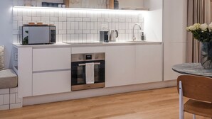 A modern kitchen with white cabinetry, a built-in microwave, and a coffee maker. - Seaside 9: Modern Studio with Balcony & Ocean View (Cape Town)