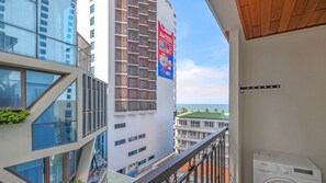 A balcony with a view of the ocean, modern buildings, and a Samsung washing machine. - Viela Apartment Nha Trang  (Nha Trang)
