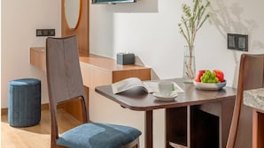 A modern dining area with wooden chairs and a table, a mounted television, and a vase with flowers.