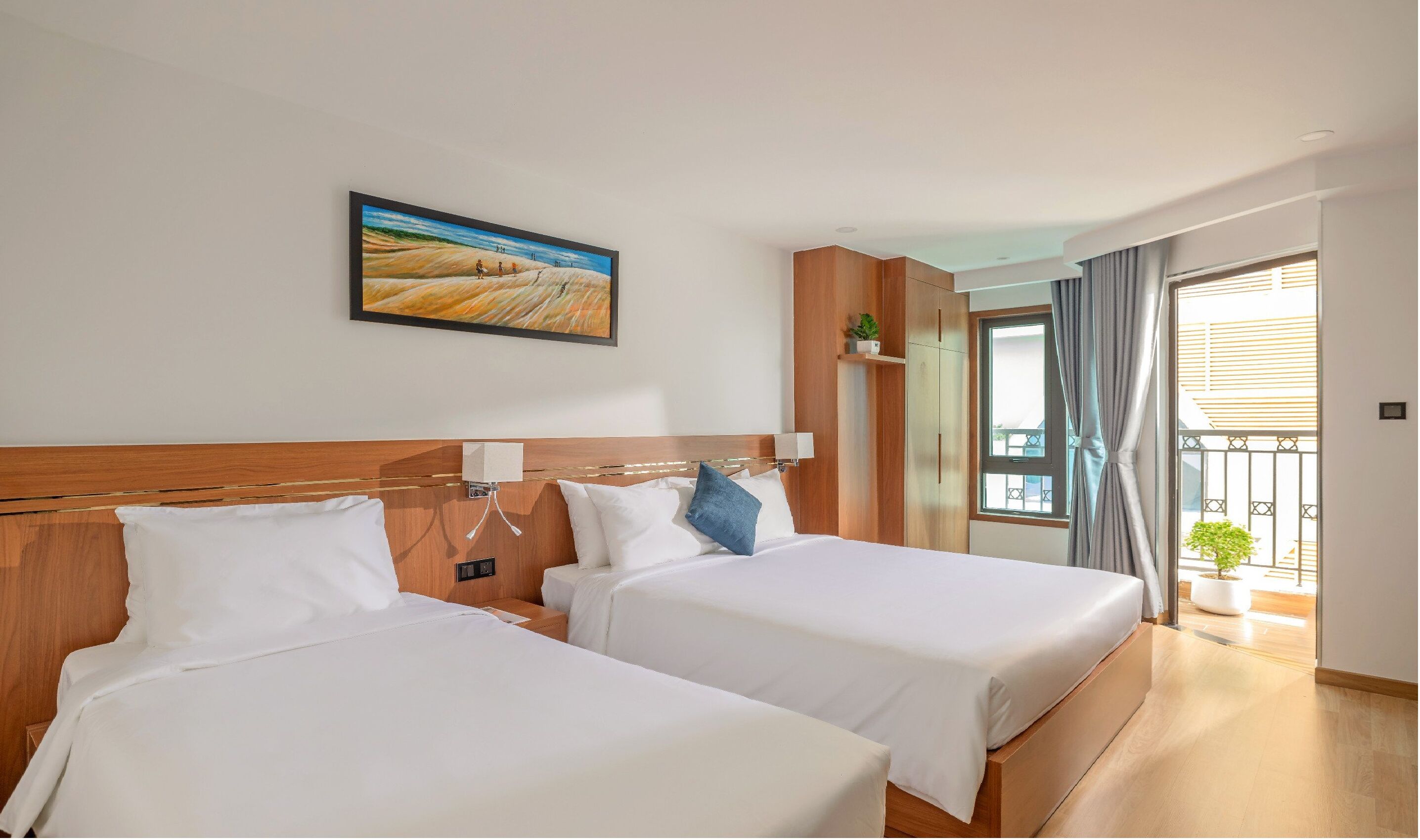 A hotel room with two beds, a painting on the wall, a window with curtains, and a view of the outside.