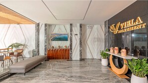 A modern lobby with a marble floor, a reception desk, a sofa, and a large sign for Vila Apartment.