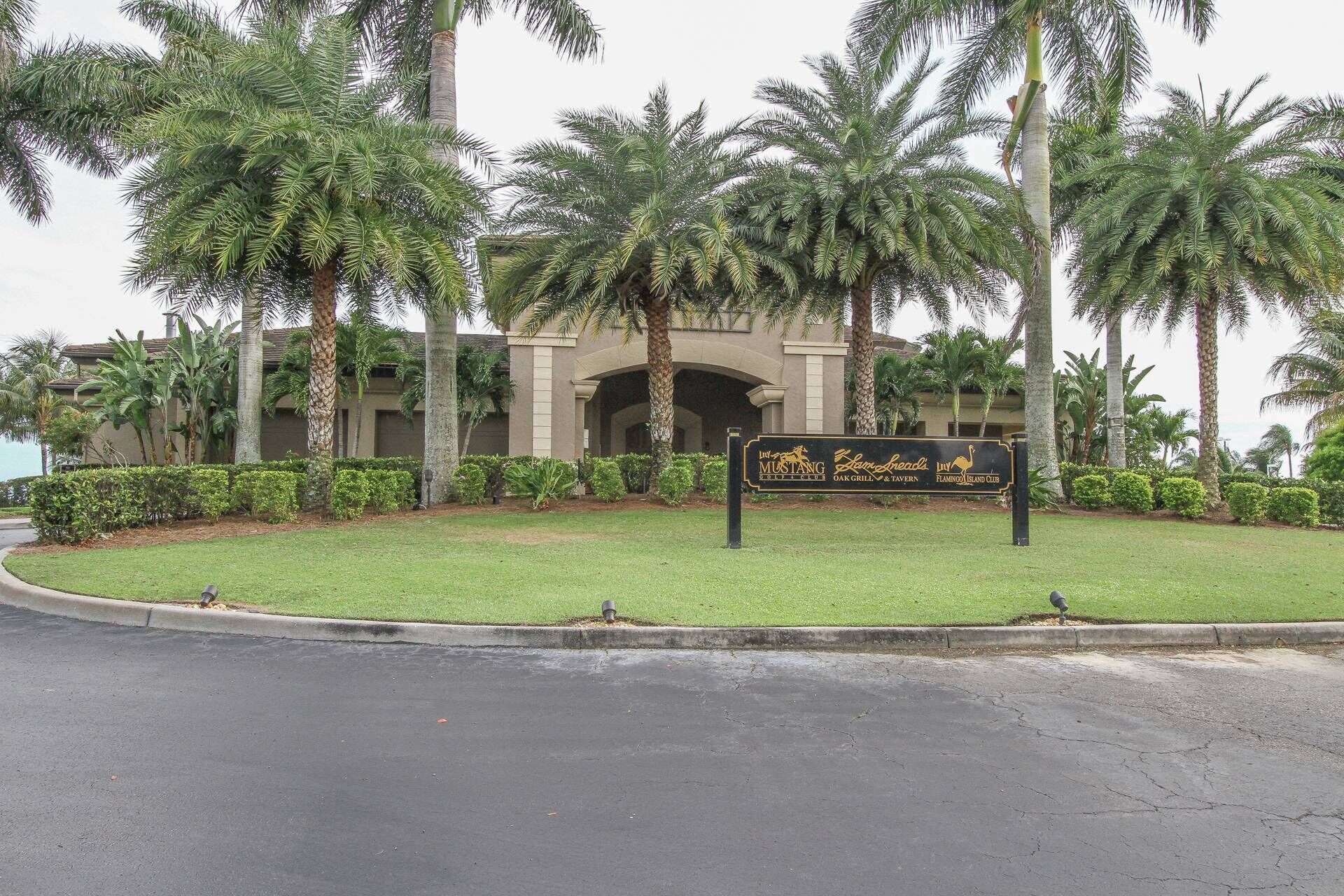 A sign for The Flamingo Island Club with a building in the background.