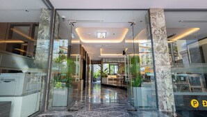 A modern hotel lobby with glass doors, a marble floor, and a view of the street outside. - Stella Hotel & Apartment (Ho Chi Minh City)