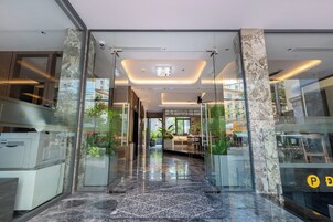 Un moderno vestíbulo de hotel con puertas de vidrio, suelo de mármol y vistas a la calle.