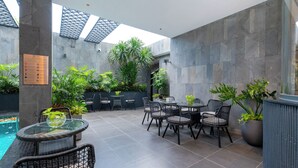 A modern outdoor patio with a pool, seating area, and potted plants. - Stella Hotel & Apartment (Ho Chi Minh City)