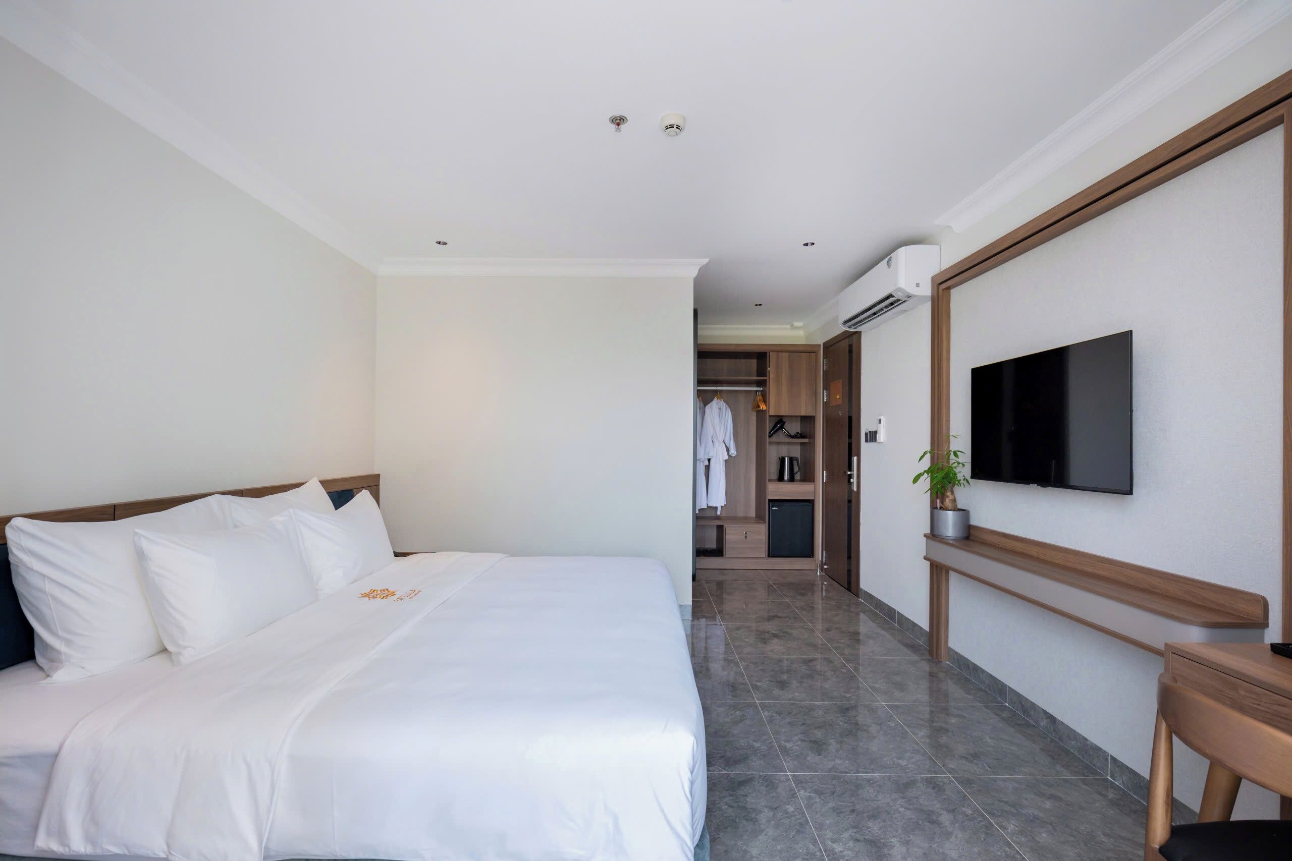 Ein Hotelzimmer mit einem großen Bett, einem an der Wand befestigten Fernseher und einem begehbaren Kleiderschrank.