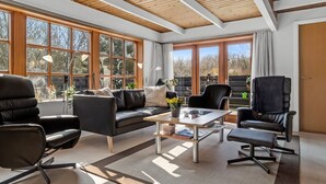 A spacious living room with a modern design, featuring a black leather sofa, two black leather chairs, a wooden coffee table, and large windows offering a view of the outdoors. - "Berner" - 30km from the sea by Interhome (Toftlund)