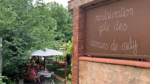 An outdoor seating area with a chalkboard sign reading "restauration gîte des saveurs du lady". - Gîte du Cady (Casteil)
