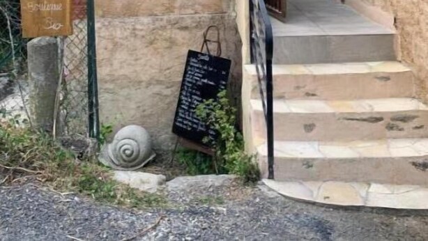 A rustic stone building with a wooden signboard and a chalkboard menu. - Gîte du Cady (Casteil)