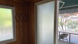 A room with wooden walls, a sliding glass door, and a small outdoor area with a grill. - MAUMAEGOHYANG Pension (Cheongdo)