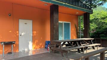 A wooden deck with picnic tables, a door, and a small trash bin.