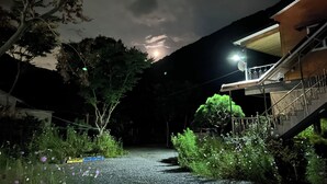 A nighttime view of a building with a staircase and a garden area with various plants and flowers. - MAUMAEGOHYANG Pension (Cheongdo)