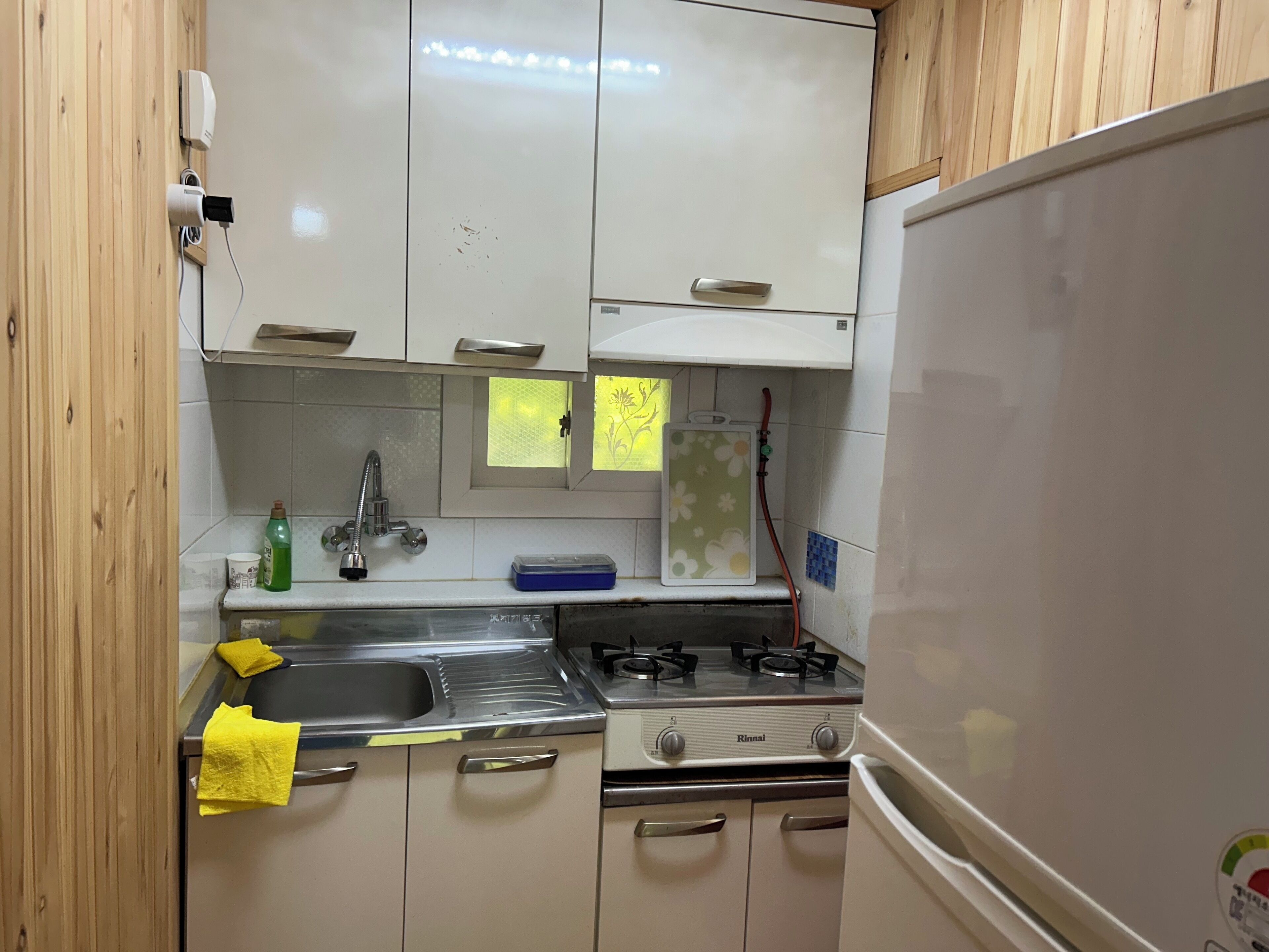 A compact kitchen with white cabinets, a stainless steel sink, a gas stove, and a white refrigerator.