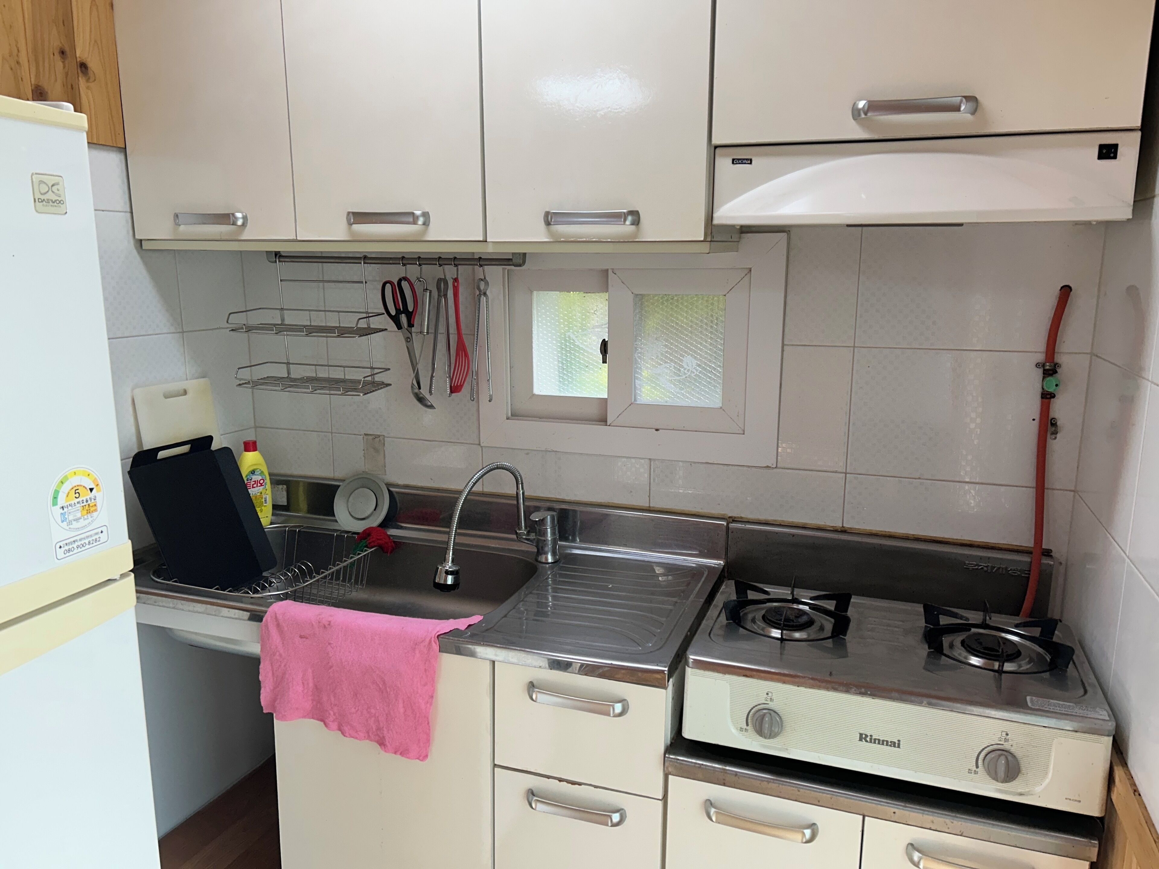 Una cocina compacta con refrigerador, lavamanos y estufa a gas.