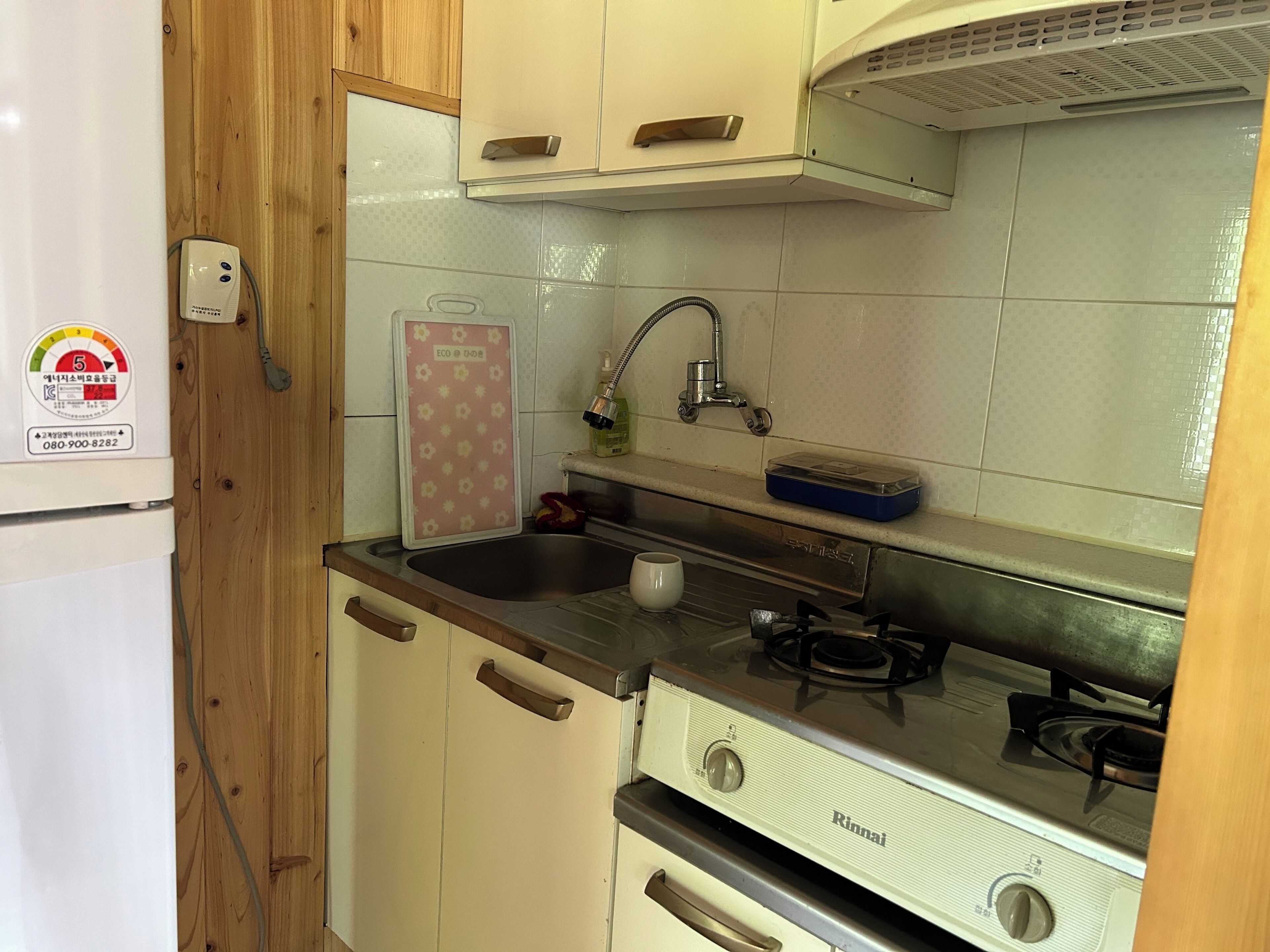 A compact kitchen with a gas stove, a sink, and wooden cabinets.